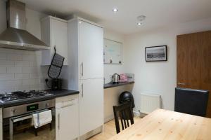 a kitchen with white cabinets and a wooden table at Modern, 2 Bdrm House Town Centre, North Laine Sleeps 6 in Brighton & Hove