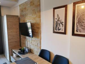 a dining room with a table and a television on a wall at SkyKop Apartman L21 in Kopaonik