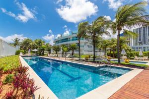a pool at a resort with palm trees and a building at In Mare Bali #138 - Flat em Cotovelo por Carpediem in Parnamirim