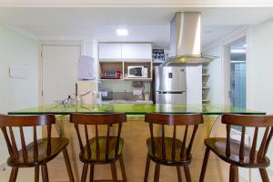 a kitchen with a glass counter top and wooden stools at In Mare Bali #138 - Flat em Cotovelo por Carpediem in Parnamirim