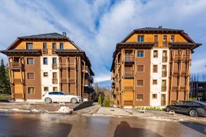 two tall buildings with cars parked in front of them at V&Dj in Zlatibor