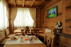 a dining room with a table with food and a television at Agritur Melissa in Croviana