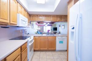 a kitchen with wooden cabinets and a white refrigerator at Soundside Holiday Beach Resort in Pensacola Beach