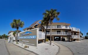 un edificio con palme e un cartello di fronte ad esso di Soundside Holiday Beach Resort a Pensacola Beach