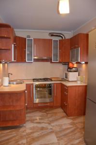 kuchnia z drewnianymi szafkami i kuchenką mikrofalową w obiekcie Apartament u Katarzyny w mieście Grodzisk Mazowiecki