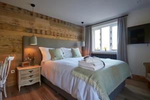 a bedroom with a large bed with a wooden wall at Wild Thyme & Honey in Cirencester