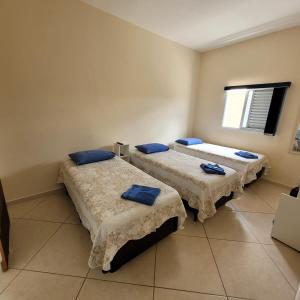 a room with three beds with blue pillows in it at Pousada Dona Helena in Morungaba