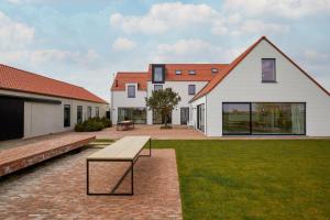 a house with a bench in the middle of a yard at DOS22 Vakantiewoning I De Haan Wenduine in Zuienkerke