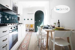 a kitchen with a table with white chairs and a green door at Casa Le Calle in Positano