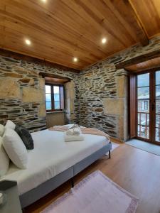 a bedroom with a large bed in a stone wall at O Chouzal in Arouca