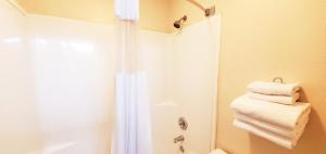y baño con ducha y toallas blancas. en Westlake Inn en Strathmore