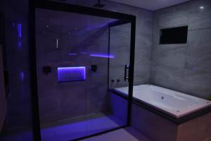 a bathroom with a shower and a tub with a blue light at Desejo Motel in Araçoiaba da Serra