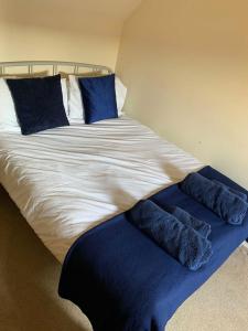 a large bed with blue pillows on top of it at Bright House with Garden & Patio in Market Town in Inverurie