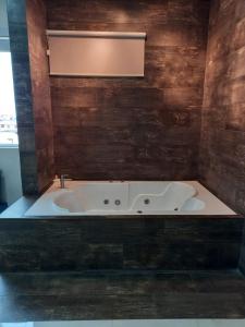 y baño con bañera grande y paredes de madera. en Hotel La Ría Durán, en Durán
