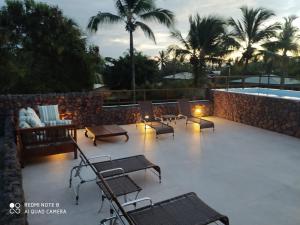 a patio with chairs and a pool with palm trees at Praia do Forte Ohana Residence in Praia do Forte