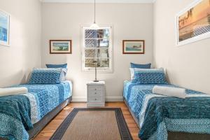 1 dormitorio con 2 camas individuales y ventana en Wambiri on Lighthouse Road en Byron Bay