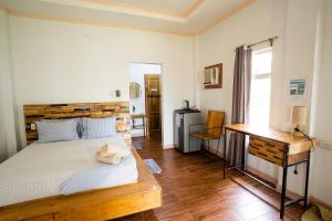 1 dormitorio con cama con cabecero de madera y escritorio en YAMA APARTMENTS - Private Beachfront, en General Luna