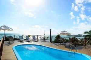 ein Swimmingpool auf einer Terrasse mit Tischen und Sonnenschirmen in der Unterkunft Marsallis Praia - Flat 404 - Vista Mar in Natal