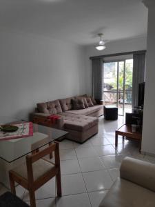 uma sala de estar com um sofá e uma mesa em Enseada- 400m Aquário. Apt espaçoso e aconchegante no Guarujá