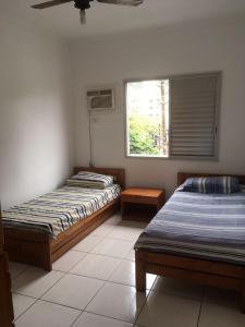 Duas camas num quarto com uma janela em Enseada- 400m Aquário. Apt espaçoso e aconchegante no Guarujá