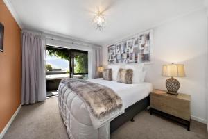 - une chambre avec un grand lit et une fenêtre dans l'établissement Distinctive Alpine Meadows, à Queenstown