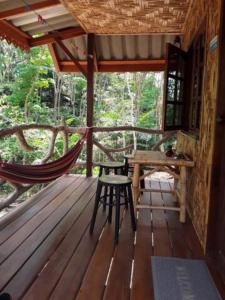 eine Hängematte und ein Tisch auf einer Veranda einer Hütte in der Unterkunft Treehouse Holidays-Love Nest in Ko Yao Noi