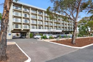 un gran edificio con coches estacionados en un estacionamiento en The Plaza Hotel Kalgoorlie en Kalgoorlie