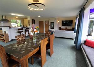 a dining room and living room with a table and chairs at Labyrinth Gardens Guest House in Takaka