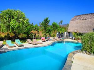 a swimming pool with chaises and chairs next to a resort at Bunga Laut Bungalow in Amed