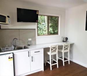 a kitchen with white cabinets and a sink and a window at Vista Hinchinbrook in Cardwell