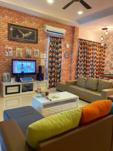 a living room with a couch and a tv at Sitiawan Paradise Teluk Batik Karaoke Snooker BBQ 15Pax in Lumut