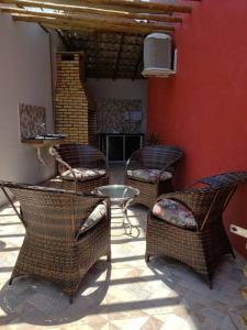 a patio with wicker chairs and a table and a red wall at Chaleville Coqueiro 1001 in Luis Correia