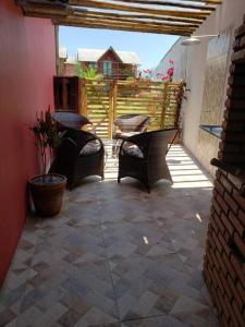 a patio with wicker chairs and a table and a house at Chaleville Coqueiro 1001 in Luis Correia