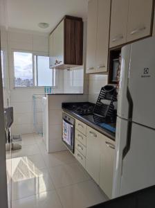 een keuken met een koelkast en een fornuis top oven bij APARTAMENTO - GUILHERMINA - PRAIA GRANDE in Praia Grande