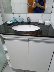 a woman taking a picture of a bathroom sink at Chaleville Coqueiro 1001 in Luis Correia