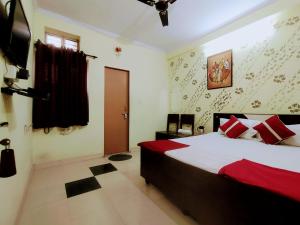 a bedroom with a bed with red and white pillows at Satkar Hotel in Jaipur