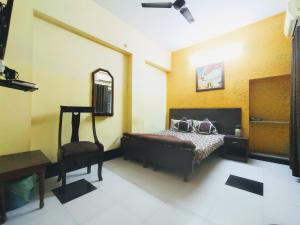 a bedroom with a bed with a chair and a mirror at Satkar Hotel in Jaipur