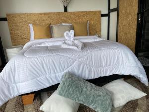 Una gran cama blanca con un animal de peluche. en Balú Glamping en San Francisco