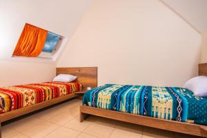 a bedroom with two beds with colorful blankets at The Traveler Hostel in Otavalo