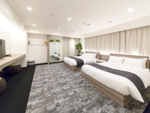 um quarto de hotel com duas camas e uma televisão em H.B.P HOTEL em Osaka