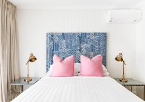 a bedroom with a bed with pink pillows at The Lord Byron in Byron Bay