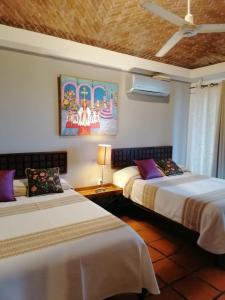 een slaapkamer met 2 bedden en een schilderij aan de muur bij Casa Maria en La Manzanilla in La Manzanilla