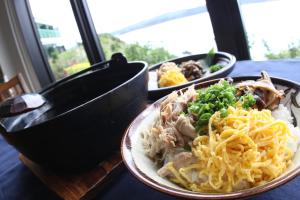 a plate of food on a table with noodles and meat at Native Sea Amami Adan On The Beach in Tatsugo