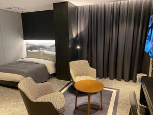 安城市的住宿－Anseong City Hotel，卧室配有一张床和一张桌子及椅子