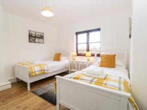 a bedroom with two beds and a window at Stable Cottage in Winscombe