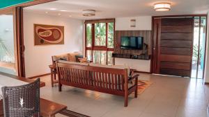 a living room with a couch and a television at Cores do Arraial Residence Hotel in Arraial d'Ajuda