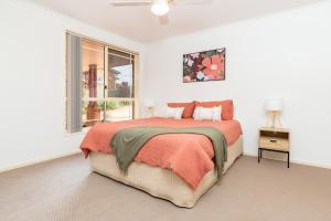 a white bedroom with a bed and a window at Lakeview on Victoria in Forster