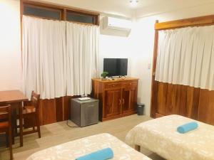 a room with two beds and a desk and a television at Pahiluna Guesthouse in Panglao
