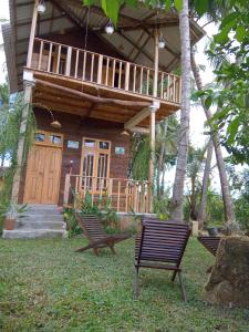 une maison en bois avec deux bancs devant elle dans l'établissement Coconut Island Yala, à Tissamaharama
