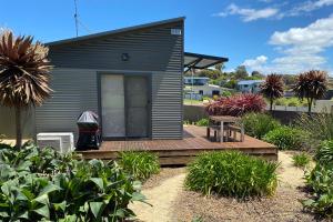 une petite maison avec une terrasse en bois et un banc dans l'établissement Fairways 1, à Coles Bay